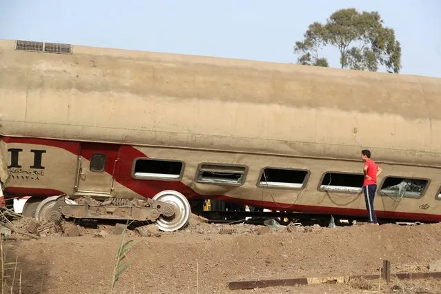 A boy stands at the site where train carriages derailed in Qalioubia province, north of Cairo, Egypt on April 18, 2021. (Photo by Mohamed Abd El Ghany/Reuters)