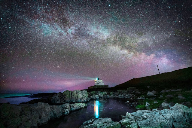 The core of the Milky Way becomes visible in the early hours of Tuesday morning as it moves over Bamburgh Lighthouse at stag Rock in Northumberland on Tuesday, April 13, 2021. (Photo by Owen Humphreys/PA Images via Getty Images)
