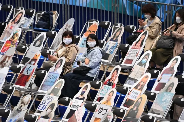 Spectators sit among the figures with pictures of the fans and animals ahead of the ISU World Team Trophy figure skating event in Osaka on April 15, 2021. (Photo by Philip Fong/AFP Photo)