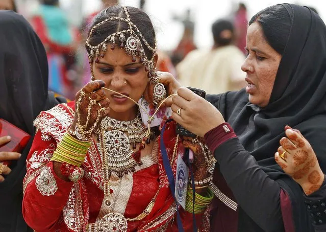 A Muslim bride is helped with her ornaments, before the start of a mass marriage ceremony in the western Indian city of Ahmedabad, February 15, 2015. (Photo by Amit Dave/Reuters)