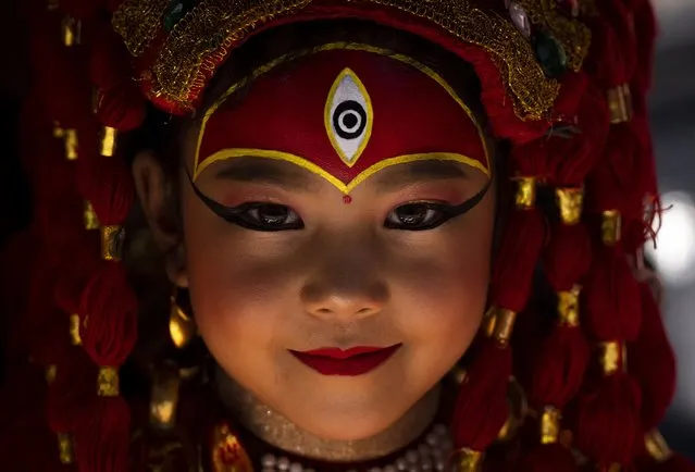 A young girl dressed as living goddess Kumari reacts to the camera as she waits for Kumari Puja, a worship ritual at Hanuman Dhoka, Basantapur Durbar Square, Kathmandu, Nepal, Wednesday, September 27, 2023. Girls under the age of nine gathered for the tradition of worshiping young prepubescent girls as manifestations of the divine female energy. The ritual holds a strong religious significance in the Newar community that seeks divine blessings to save small girls from diseases and bad luck in the years to come. (Photo by Niranjan Shrestha/AP Photo)