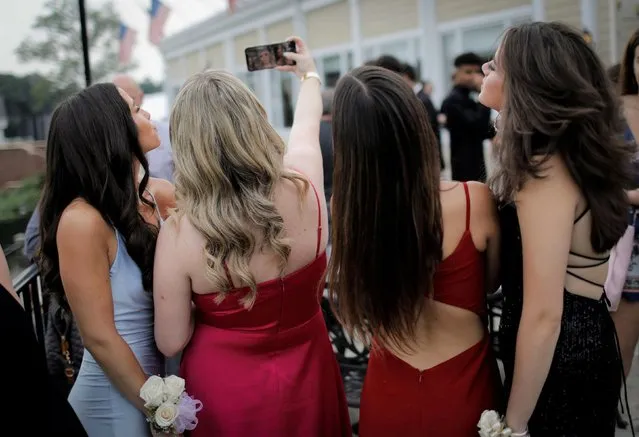 Young women take a selfie photograph in their prom dresses at a pre-prom gathering before the Dwight Englewood School senior prom at the Knickerbocker Country Club in Tenafly, New Jersey, U.S., June 7, 2021. (Photo by Mike Segar/Reuters)
