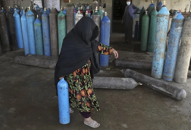 A woman carries an oxygen cylinder from a privately owned oxygen factory, in Kabul, Afghanistan, Saturday, June 19, 2021. Health officials say Afghanistan is fast running out of oxygen as a deadly third surge of COVID worsen. (Photo by Rahmat Gul/AP Photo)