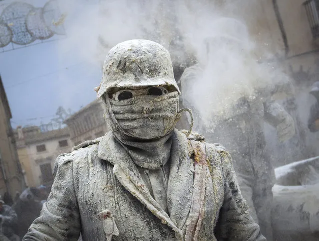 Revellers dressed in mock military garb take part in the “Enfarinats” battle in the southeastern Spanish town of Ibi on December 28, 2016. During this 200-year-old traditional festival participants known as Els Enfarinats (those covered in flour) dress in military clothes and stage a mock coup d'etat as they battle using flour, eggs and firecrackers outside the city town hall as part of the celebrations of the Day of the Innocents. (Photo by Jaime Reina/AFP Photo)