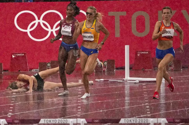 Sara Petersen, of Denmark, left, falls as Femke Bol, of Netherlands, right, races to win a heat of the women's 400-meter hurdles at the 2020 Summer Olympics, Monday, August 2, 2021, in Tokyo, Japan. (Photo by Charlie Riedel/AP Photo)