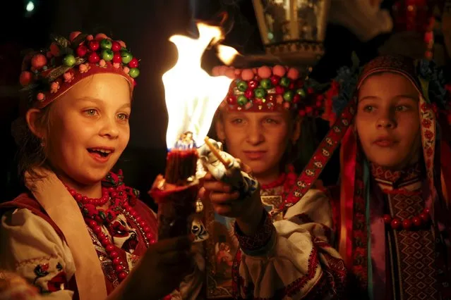 Children dressed in traditional Ukrainian clothing light candles during the Holy Fire ceremony on the eve of Orthodox Easter service in front of Volodymysky Cathedral in Kiev April 11, 2015. (Photo by Valentyn Ogirenko/Reuters)