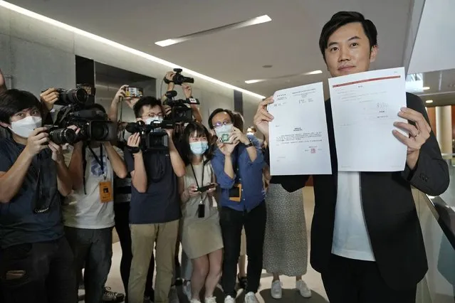 Lawmaker Cheng Chung-Tai displays a document as he is surrounded by reporters after being disqualified from the legislature in Hong Kong, Thursday, August 26, 2021. Hong Kong authorities ousted Cheng from his seat Thursday after finding him to be insufficiently loyal amid Beijing’s tightening grip on the semi-autonomous city. (Photo by Vincent Yu/AP Photo)