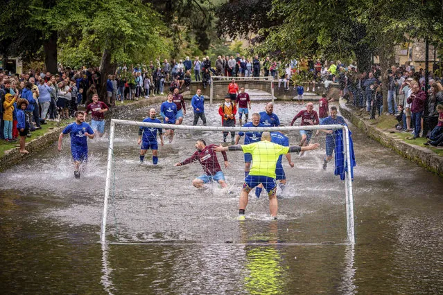 Footballers from Bourton Rovers fight for the ball in the River Windrush during the annual traditional river football match in the Cotswolds village of Bourton-in-the-Water, England, Monday, August 30, 2021. (Photo by Ben Birchall/PA Wire via AP Photo)