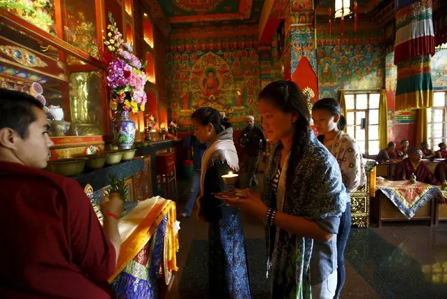 Daughters of Aan Kaji Sherpa, one of the 16 Nepali Sherpa guides who were killed during an avalanche last year, light butter lamps in memory of their father at a monastery in Kathmandu April 18, 2015. (Photo by Navesh Chitrakar/Reuters)