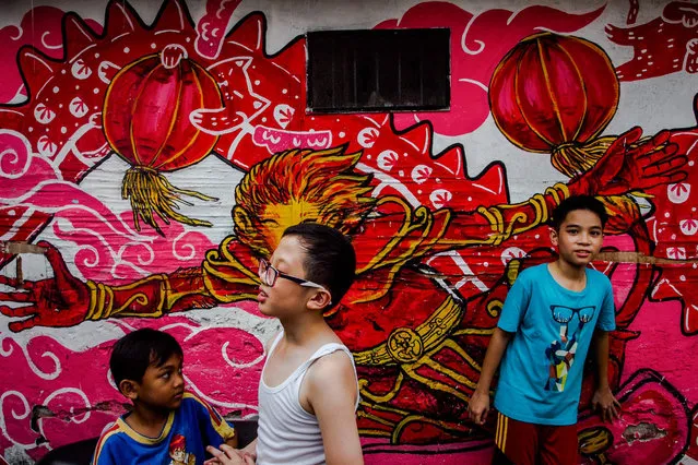 Indonesian boys play in front of Chinese a Lunar New Year mural at the China town Surabaya, East Java, Indonesia, 27 January  2017. The Chinese population of Indonesia prepares to welcome the Chinese Lunar New Year, which falls on 28 January in 2017. (Photo by Fully Handoko/EPA)