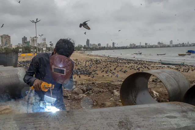 A worker welds an iron pole at a construction site by the Arabian sea shore in Mumbai, India, Tuesday, September 28, 2021. (Photo by Rafiq Maqbool/AP Photo)