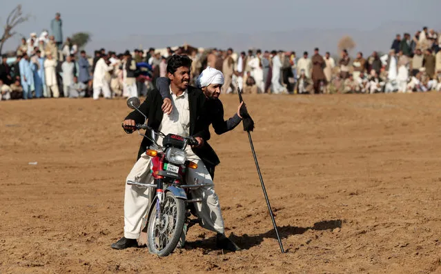 A bull savar (jockey), getting a motorcycle ride back to the start line, watches bulls run through spectators during a bull race in Pind Sultani, Pakistan January 31, 2017. (Photo by Caren Firouz/Reuters)