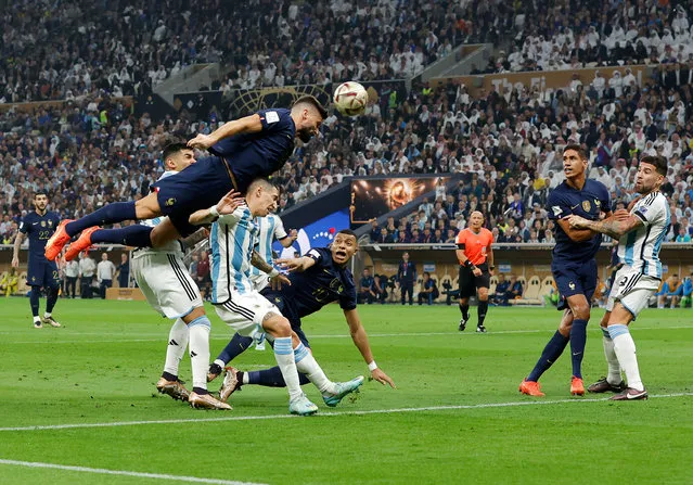 Olivier Giroud of France leaps above Angel Di Maria and Cristian Romero of Argentina to head goalwards only to be awarded a free kick against im for a foul during the FIFA World Cup Qatar 2022 Final match between Argentina and France at Lusail Stadium on December 18, 2022 in Lusail City, Qatar. (Photo by Tom Jenkins/The Guardian)