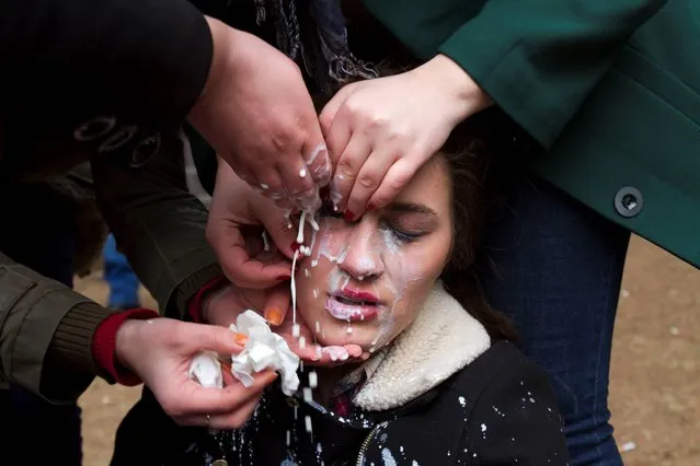 Students pour milk on a fellow student's eyes after Kosovo police officers used pepper spray to prevent them from storming the building of the main public Pristina University on Thursday, February 6, 2014. Hundreds of protesters are locked in a stand-off with Kosovo special police units outside the offices of the dean of the main public university and are demanding he resign following accusations of corruption and mismanagement. (Photo by Visar Kryeziu/AP Photo)