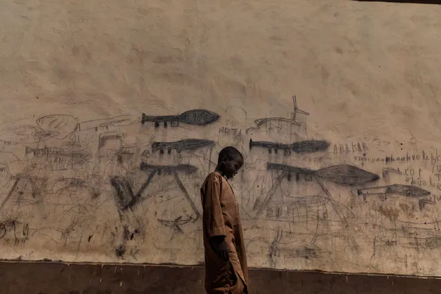Environment, stories winner: Almajiri Boy, by Marco Gualazzini. An orphaned boy walks past drawings on a wall depicting rocket-propelled grenade launchers, in Bol, Chad. This image was also nominated as part of a set in the “photo story of the year” and “environment story” categories. (Photo by Marco Gualazzini/Contrasto/World Press Photo 2019)