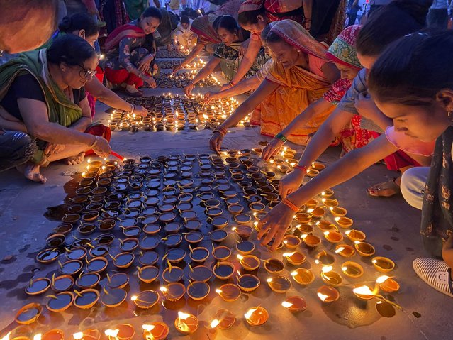 People light lamps on the banks of the river Saryu in Ayodhya, India, Wednesday, November 3, 2021. (Photo by Rajesh Kumar Singh/AP Photo)