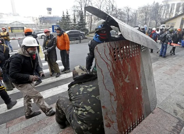 Two anti-government protesters stand behind a blood stained shield after violence erupted in the Independence Square in Kiev February 20, 2014. (Photo by Vasily Fedosenko/Reuters)