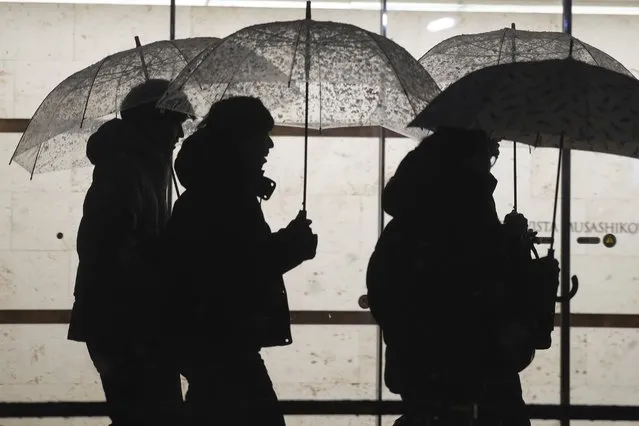 People are silhouetted as they use umbrellas to shelter from a snowfall, in Tokyo, Monday, February 5, 2024. (Photo by Eugene Hoshiko/AP Photo)