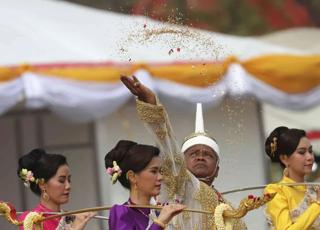 The leader of the plowing ceremony Anan Suwannart throws rice seeds into the field during the royal event in Bangkok, Thailand, Thursday, May 9, 2019. The annual event marks the beginning of the growing season in Thailand for rice. (Photo by Sakchai Lalit/AP Photo)