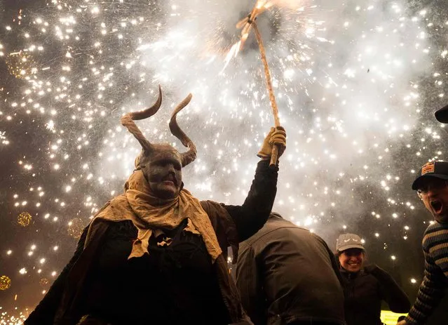 A participant dressed up as a demon holds a stick with fireworks during the traditional Correfoc (fire-run) festival in Palma de Mallorca on January 29, 2023. The Correfoc is a night of revelry in which participants dress up as demons and devils, and run through the streets scaring people with fire and fireworks. (Photo by Jaime Reina/AFP Photo)