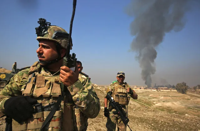 Smoke billows in the background as Iraqi forces advance on February 23, 2017 towards Mosul airport on the southern edge of the jihadist stronghold entering the compound for the first time since the Islamic State group overran the region in 2014. Backed by jets, gunships and drones, forces blitzed their way across open areas south of Mosul and entered the airport compound, apparently meeting limited resistance but strafing the area for suspected snipers. (Photo by Ahmad Al-Rubaye/AFP Photo)