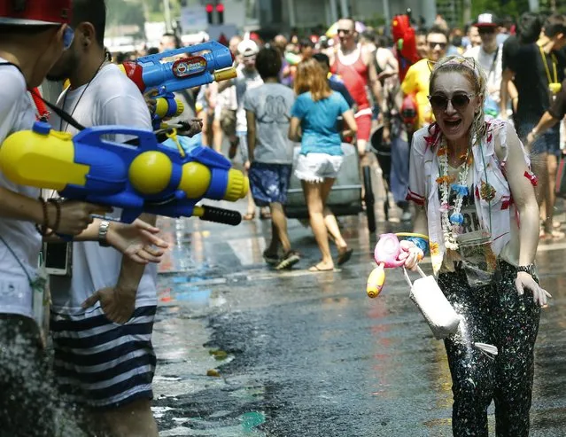 A tourist plays with water as they join the annual Songkran Festival celebration, the Thai traditional New Year, also known as the water festival, in Silom district of Bangkok, Thailand, 13 April 2016. The three-day Songkran Festival starts on 13-15 April annually and is celebrated with splashing water and putting powder on each others faces as a symbolic sign of cleansing and washing away the sins from the old year. (Photo by Narong Sangnak/EPA)