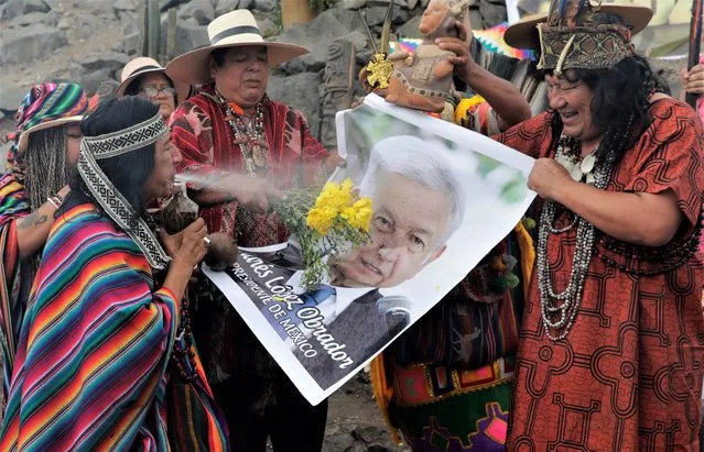 Shamans use a photo of Mexico's President Andres Manuel Lopez Obrador during a year-end ritual where they predict political and social issues expected to occur in next year in Lima, Peru, Wednesday, December 29, 2021. The shamans made symbolic payment to Mother Earth while asking that the COVID-19 pandemic come to an end and that world leaders be cleansed so they can make wise decisions in the coming year. (Photo by Guadalupe Pardo/AP Photo)