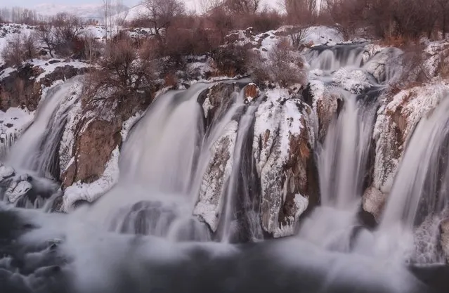 A view from partly frozen Muradiye Waterfall during winter season in Muradiye district of Turkey's eastern Van province on December 26, 2021. Temperature dropped down to 18 Celsius degrees below zero, freezing part of the waterfall. (Photo by Necmettin Karaca/Anadolu Agency via Getty Images)