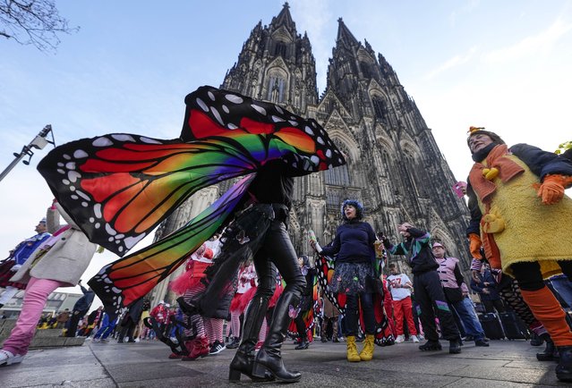 Revellers dance in front of the Cologne Cathedral at the start of the street carnival in Cologne, Germany, Thursday, February 16, 2023. Hundreds of thousands will celebrate the carnival without any coronavirus restrictions in the streets of the German carnival capital. (Photo by Martin Meissner/AP Photo)