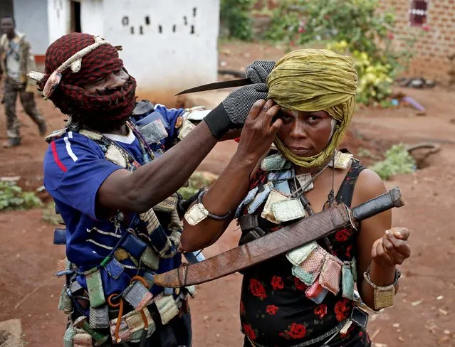 A masked member of the anti-balaka, a Christian militia, adjusts the scarf of his female comrade before they patrol the village of Zawa April 8, 2014. (Photo by Goran Tomasevic/Reuters)