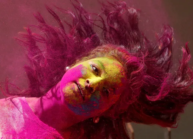 A woman smeared with coloured powder shakes her head to remove it after it was applied on her while celebrating Holi, the Festival of Colours, in Mumbai, March 13, 2017. (Photo by Shailesh Andrade/Reuters)