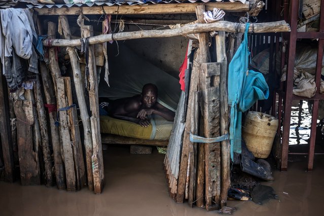 A man assess the level of the water while laying in his bed at an inundated area in Garissa, on May 9, 2024. Kenya is grappling with one of its worst floods in recent history, the latest in a string of weather catastrophes, following weeks of extreme rainfall scientists have linked to a changing climate. At least 257 people have been killed and more than 55,000 households have been displaced as murky waters submerge entire villages, destroy roads and inundate dams. (Photo by Luis Tato/AFP Photo)