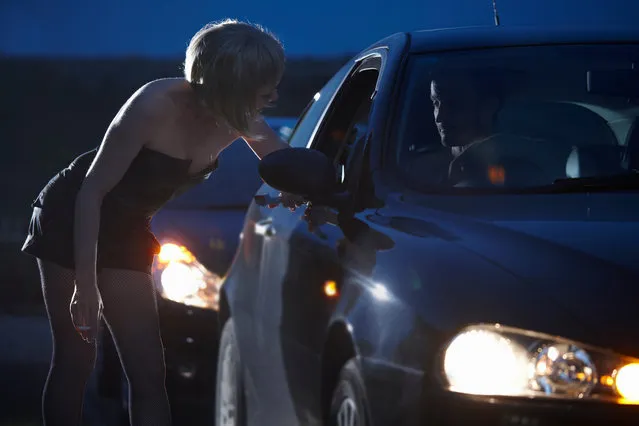 Motorist talking to prostitute in street at night. (Photo by Andrew Bret Wallis/Getty Images)