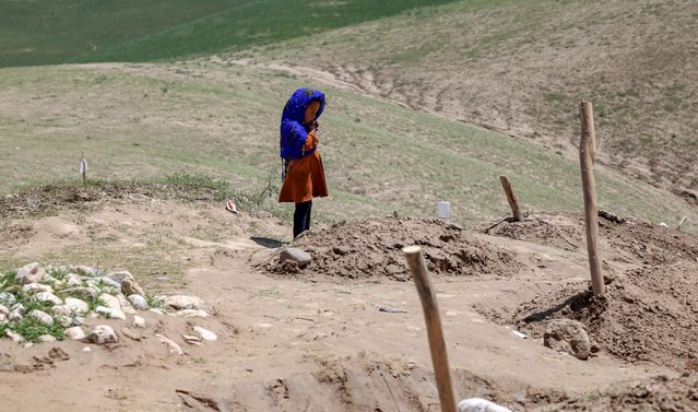 A girl, who lost four of her family members, stands beside the grave of her brother in flood-hit Sherjalal village in Baghlan, Afghanistan, 12 May 2024. At least 300 people have died amid heavy floods in Baghlan province in northern Afghanistan, the United Nations Food Program (WFP) said on 11 May. The Asian country is one of the world's most vulnerable to climate change and the least prepared to adapt, according to a report by the United Nations Office for the Coordination of Humanitarian Affairs (OCHA). Much of the country's international aid and funding were frozen after the Taliban seized power in August 2021. (Photo by Samiullah Popal/EPA/EFE)