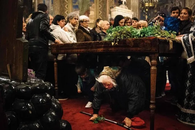 Bulgarian East-Orthodox believers pray and pass under a table where the Bible is placed during a Good Friday service at Alexander Nevsky Cathedral in Sofia on April 14, 2017. (Photo by Dimitar Dilkoff/AFP Photo)