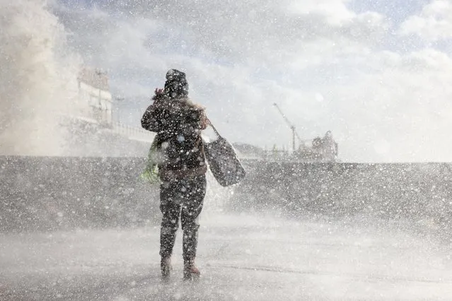 A young woman braves the elements as Storm Eunice causes large waves to crash against the seawall alongside Brighton Pier on February 18, 2022 in Brighton, England. The Met Office has issued two rare, red weather warnings for the South and South West of England today as Storm Eunice makes landfall. Much of the rest of the UK is under amber and yellow warnings with winds up to 100 mph, rain and snow expected. This is the worst storm to hit the UK for three decades. (Photo by Dan Kitwood/Getty Images)