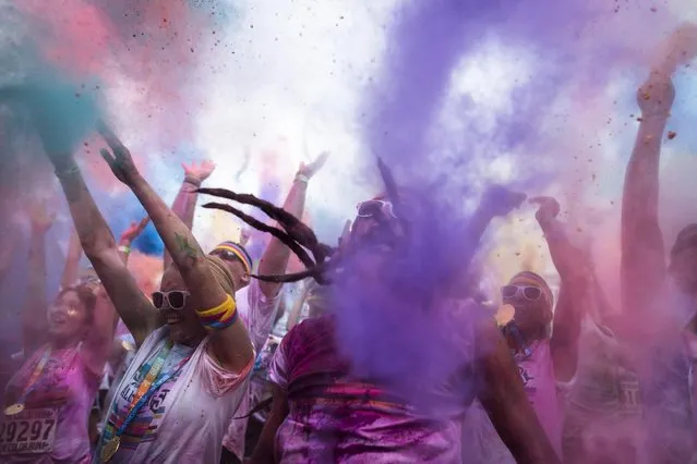 Runners frolic in a haze of colored powder in Sawyer Point Park after completing The Color Run All-Star 5K as part of the All-Star Baseball game festivities, Saturday, July 11, 2015, in Cincinnati. (Photo by John Minchillo/AP Photo)
