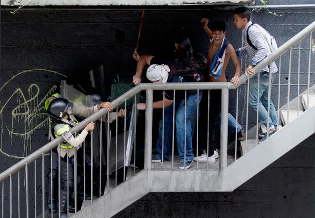 Anti-government demonstrators fight with Bolivarian National police on a pedestrian bridge during an anti-government march toward the headquarters of the national electoral body, CNE, in Caracas, Venezuela, Wednesday, May 18, 2016. (Photo by Fernando Llano/AP Photo)