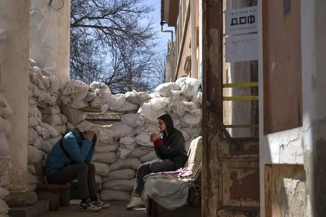 A volunteer smokes next to sandbags used for protection, at a Ukrainian volunteer center in Mykolaiv, southern Ukraine, on Monday, March 28, 2022. (Photo by Petros Giannakouris/AP Photo)