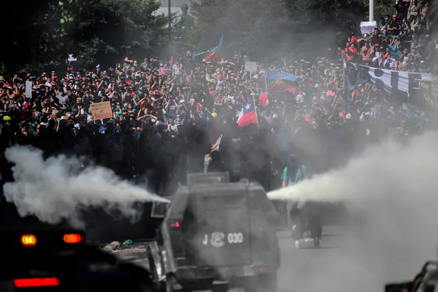 Riot police try to disperse demonstrators during the fifth straight day of street violence which erupted over a now suspended hike in metro ticket prices, in Santiago, on October 22, 2019. President Sebastian Pinera convened a meeting with leaders of Chile's political parties on Tuesday in the hope of finding a way to end street violence that has claimed 15 lives, as anti-government campaigners threatened new protests. (Photo by Martin Bernetti/AFP Photo)