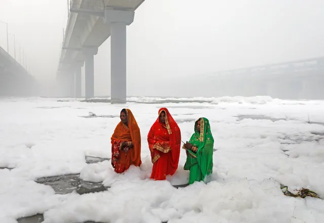 Hindu women worship the Sun god in the polluted waters of the river Yamuna during the Hindu religious festival of Chatth Puja in New Delhi, India, November 3, 2019. (Photo by Adnan Abidi/Reuters)
