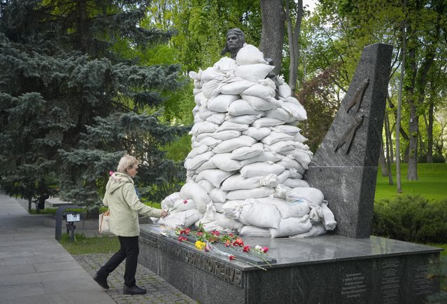 A woman lays flowers at the Unknown Soldier Tomb, protected by sandbags, on the occasion of the Victory Day in World War II, in Kyiv, Ukraine, Monday, May 9, 2022. (Photo by Efrem Lukatsky/AP Photo)