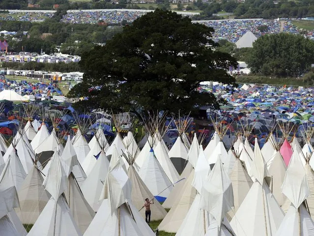 A festival goer erects a tipi at Worthy Farm in Somerset during the first day of the Glastonbury Festival. (Photo by Cathal McNaughton/Reuters)