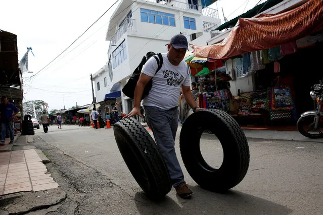 A Venezuelan man pushes tires down the street after buying them in Puerto Santander, Colombia, June 3, 2016. (Photo by Carlos Garcia Rawlins/Reuters)