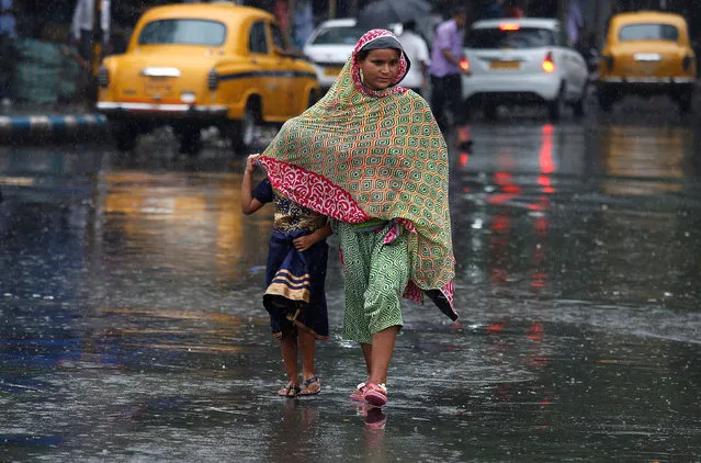 A woman shields a girl from rain as they cross a road in Kolkata, India, July 6, 2017. (Photo by Rupak De Chowdhuri/Reuters)