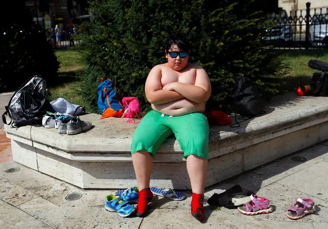 A boy takes a break from a water fight in the centre of Budapest, Hungary, June 25, 2016. (Photo by Laszlo Balogh/Reuters)