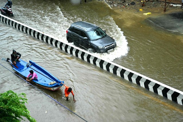 People wade through a flooded street amid heavy rainfall in Chennai on October 16, 2024. (Photo by R.Satish Babu/AFP Photo)