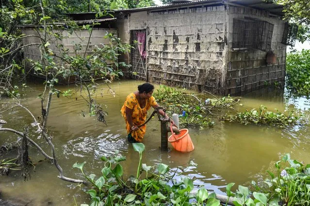 A woman fills drinking water from a tube well in the flood affected Barsimolua village in Nalbari district, in India's Assam state on June 24, 2022. (Photo by Biju Boro/AFP Photo)