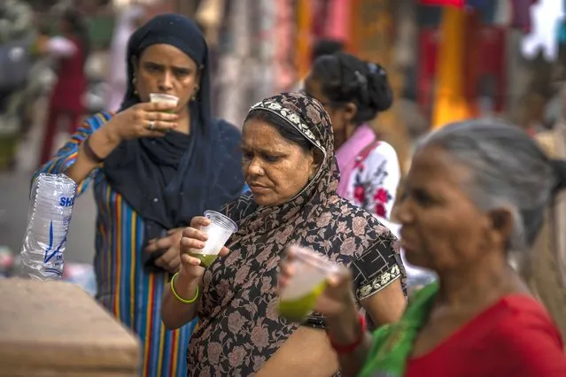Shoppers drink juice in plastic glasses as they take a break at a weekly market in New Delhi, India, Wednesday, June 29, 2022. (Photo by Altaf Qadri/AP Photo)