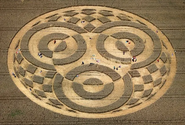 People walk through crop circles shaped into a cornfield near Raisting, southern Germany, on July 28, 2014. According to media reports, a balloonist had discovered the circle some days ago. Since then, hundreds of people came to the field to watch it, however it is unclear who did create the pattern. (Photo by Karl-Josef Hildenbrand/AFP Photo/DPA)